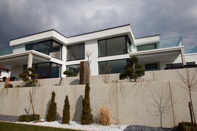 Imagen de fachada de casa blanca actual grande de dos plantas con revestimiento de estuco, tejado plano y techo verde