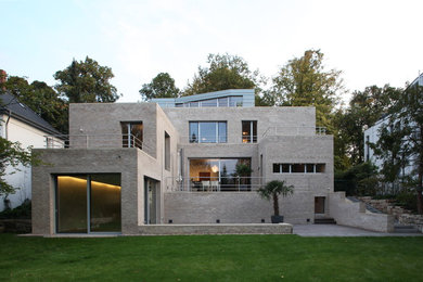 Geräumiges, Dreistöckiges Modernes Haus mit Backsteinfassade, grauer Fassadenfarbe und Flachdach in Berlin