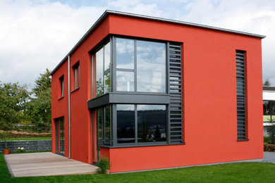 Großes, Zweistöckiges Modernes Haus mit Betonfassade, roter Fassadenfarbe und Flachdach in Sonstige