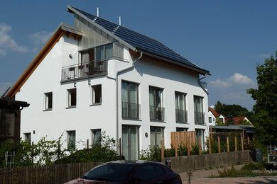 Dreistöckiges, Mittelgroßes Modernes Haus mit weißer Fassadenfarbe, Putzfassade und Pultdach in München