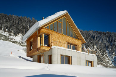 Foto della facciata di una casa marrone contemporanea a due piani con rivestimenti misti e tetto a capanna
