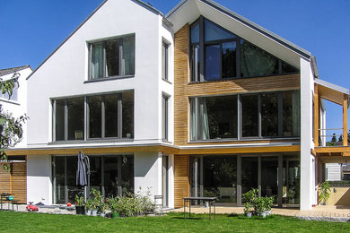 Großes, Dreistöckiges Klassisches Haus mit Mix-Fassade, weißer Fassadenfarbe und Satteldach in München