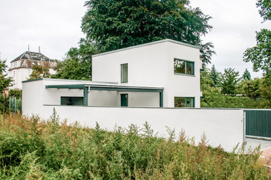 Mittelgroßes, Zweistöckiges Modernes Einfamilienhaus mit Putzfassade, weißer Fassadenfarbe und Flachdach in Sonstige