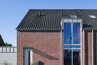 Mittelgroßes, Zweistöckiges Modernes Reihenhaus mit Backsteinfassade, brauner Fassadenfarbe, Satteldach und Ziegeldach in Düsseldorf