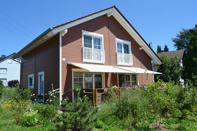 Mittelgroßes, Zweistöckiges Country Haus mit brauner Fassadenfarbe, Satteldach und Ziegeldach in Sonstige
