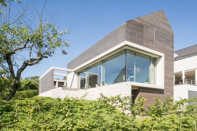Foto de fachada marrón contemporánea de tres plantas con revestimiento de madera y tejado a dos aguas
