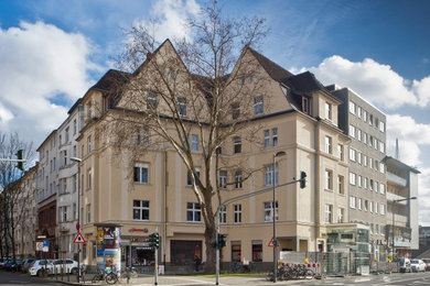 Large and beige traditional render house exterior in Cologne with three floors and a pitched roof.