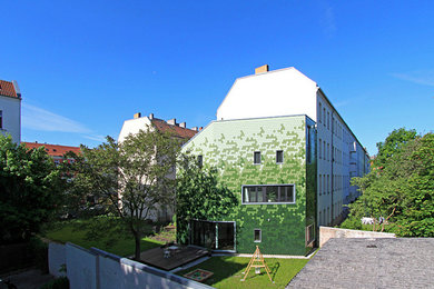 Kleines Modernes Haus mit grüner Fassadenfarbe und Flachdach in Berlin
