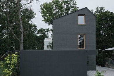 Modelo de fachada de casa negra moderna de tamaño medio de tres plantas con revestimiento de estuco, tejado a dos aguas y tejado de teja de barro