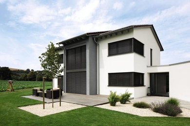 На фото: белый, двухэтажный дом среднего размера в современном стиле с облицовкой из бетона и двускатной крышей с