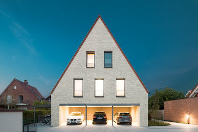 Imagen de fachada de piso beige contemporánea grande con revestimiento de ladrillo, tejado a dos aguas y tejado de teja de barro