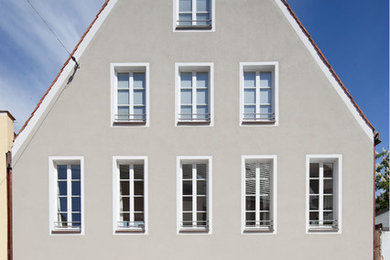 Dreistöckiges, Mittelgroßes Klassisches Haus mit grauer Fassadenfarbe und Satteldach in München