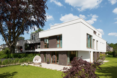 Dreistöckiges, Mittelgroßes Modernes Haus mit weißer Fassadenfarbe, Flachdach und Mix-Fassade in Hamburg