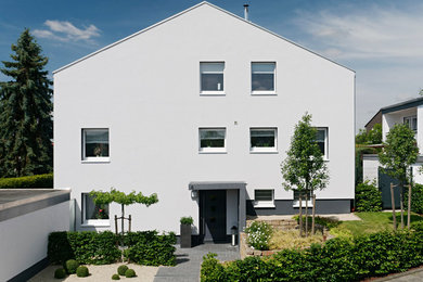 Foto de fachada blanca actual de dos plantas con revestimiento de metal y tejado a dos aguas