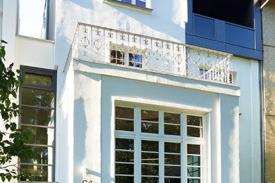 Imagen de fachada blanca tradicional de tamaño medio de tres plantas con revestimiento de estuco y tejado a dos aguas