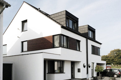 Mittelgroßes, Zweistöckiges Modernes Haus mit Putzfassade, weißer Fassadenfarbe und Satteldach in Köln