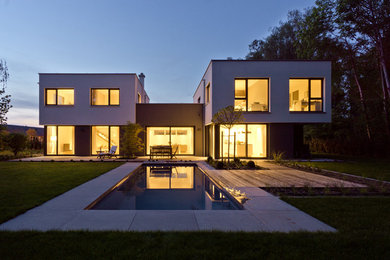 Diseño de fachada de casa negra minimalista grande de dos plantas con revestimiento de estuco, tejado plano y techo verde