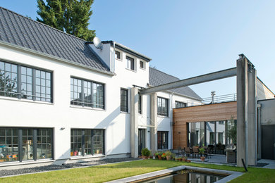 Idée de décoration pour une grande façade de maison blanche urbaine en béton à un étage avec un toit à deux pans.