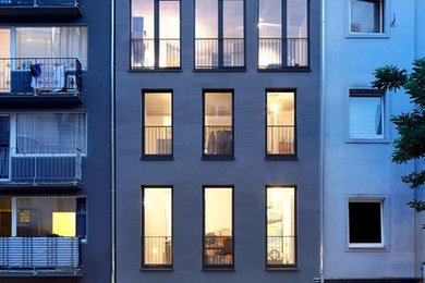 Geräumiges, Dreistöckiges Industrial Haus mit Betonfassade, grauer Fassadenfarbe und Satteldach in Düsseldorf