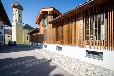 Große, Zweistöckige Landhaus Holzfassade Haus mit brauner Fassadenfarbe, Satteldach, Ziegeldach, rotem Dach und Verschalung in München