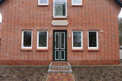 Zweistöckiges, Mittelgroßes Country Haus mit Backsteinfassade, roter Fassadenfarbe, Satteldach und Ziegeldach in Hamburg