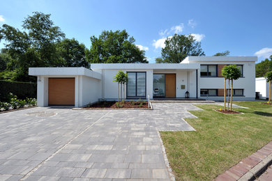 Cette photo montre une façade de maison blanche moderne en stuc à niveaux décalés et de taille moyenne avec un toit plat.