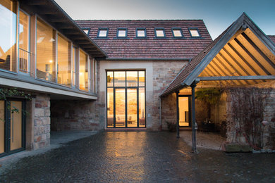 Großes, Dreistöckiges Landhausstil Einfamilienhaus mit Mix-Fassade, brauner Fassadenfarbe, Satteldach und Ziegeldach in Sonstige
