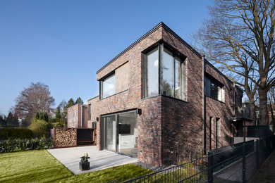 Modelo de fachada de casa marrón actual grande de dos plantas con revestimiento de ladrillo y tejado plano