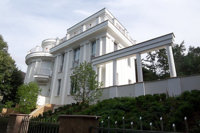 Diseño de fachada beige clásica de tamaño medio de tres plantas con revestimiento de estuco y tejado plano