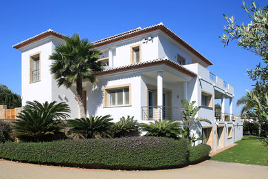Foto de fachada de casa blanca mediterránea grande de tres plantas con revestimiento de estuco y tejado de teja de madera