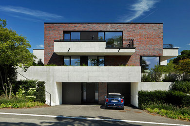 Zweistöckiges Modernes Einfamilienhaus mit Backsteinfassade, roter Fassadenfarbe und Flachdach in Sonstige