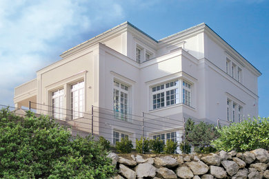 Idée de décoration pour une très grande façade de maison blanche tradition en stuc à deux étages et plus avec un toit à quatre pans.