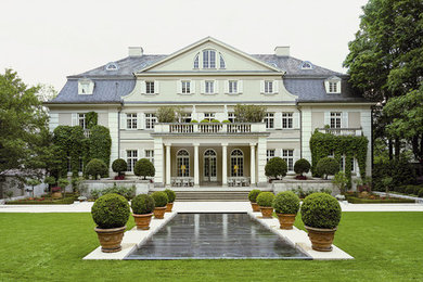 Large elegant beige three-story stucco exterior home photo in Berlin with a gambrel roof