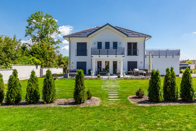 Ejemplo de fachada de casa blanca contemporánea grande de tres plantas con revestimiento de estuco, tejado a cuatro aguas y tejado de teja de barro
