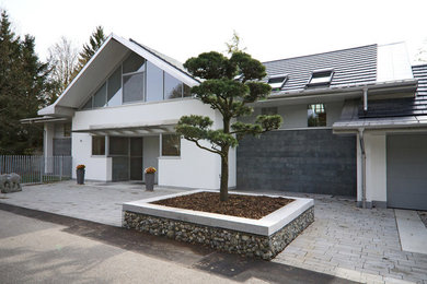 This is an example of a large and gey contemporary detached house in Frankfurt with stone cladding, a hip roof and a mixed material roof.