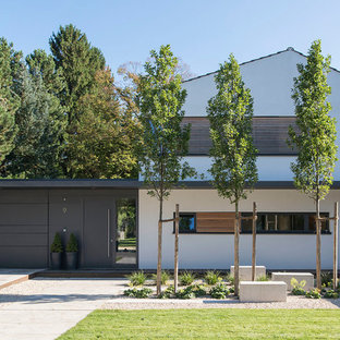 Exempel på ett stort modernt vitt hus i flera nivåer, med sadeltak