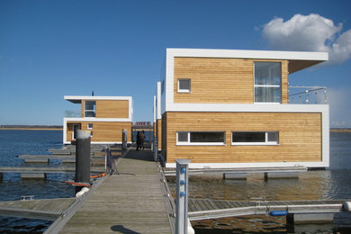 Große, Zweistöckige Maritime Holzfassade Haus mit brauner Fassadenfarbe und Flachdach in Berlin