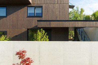 На фото: трехэтажный, деревянный, коричневый частный загородный дом среднего размера в современном стиле с двускатной крышей