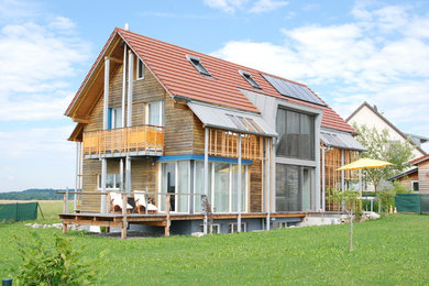 Modelo de fachada de casa contemporánea extra grande a niveles con revestimiento de madera, tejado a dos aguas y tejado de teja de barro