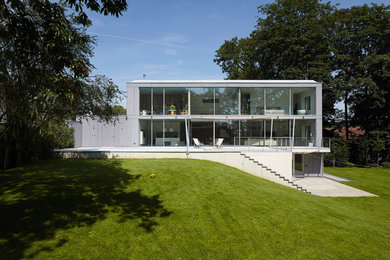 Gey and large modern two floor glass house exterior in Dusseldorf with a flat roof.