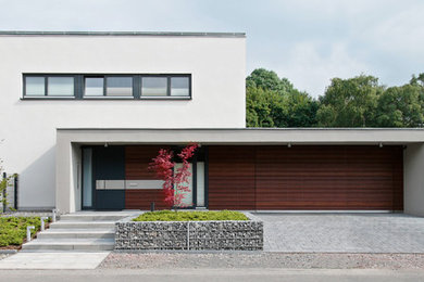 Modelo de fachada blanca minimalista de tamaño medio a niveles con tejado plano