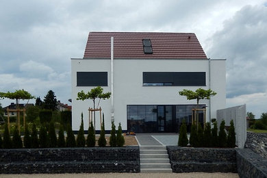 Großes, Dreistöckiges Modernes Einfamilienhaus mit Putzfassade, weißer Fassadenfarbe, Satteldach und Ziegeldach in Frankfurt am Main