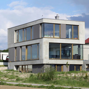 Modelo de fachada de casa gris, contemporánea, de tres plantas, con revestimiento de hormigón, tejado plano y techo verde