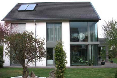 Mittelgroßes, Zweistöckiges Modernes Haus mit Putzfassade, weißer Fassadenfarbe und Satteldach in Sonstige