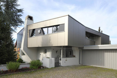 Zweistöckiges Modernes Einfamilienhaus mit Metallfassade, grauer Fassadenfarbe, Walmdach und Blechdach in Stuttgart