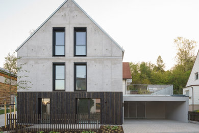 Dreistöckiges Industrial Einfamilienhaus mit Betonfassade, Satteldach, Blechdach und grauer Fassadenfarbe in München