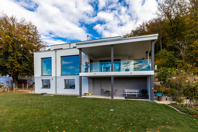 Modelo de fachada de casa blanca contemporánea grande de tres plantas con revestimiento de estuco y tejado plano