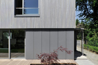 Modelo de fachada gris contemporánea de dos plantas con tejado plano y revestimiento de madera