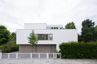 Großes, Dreistöckiges Modernes Haus mit Betonfassade, weißer Fassadenfarbe und Flachdach in München