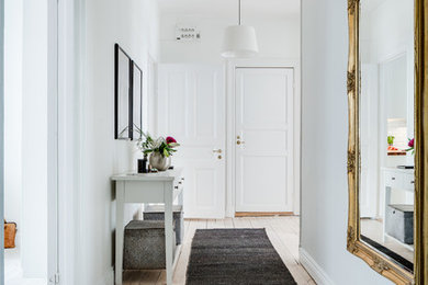 Diseño de recibidores y pasillos escandinavos de tamaño medio con paredes blancas y suelo de madera clara